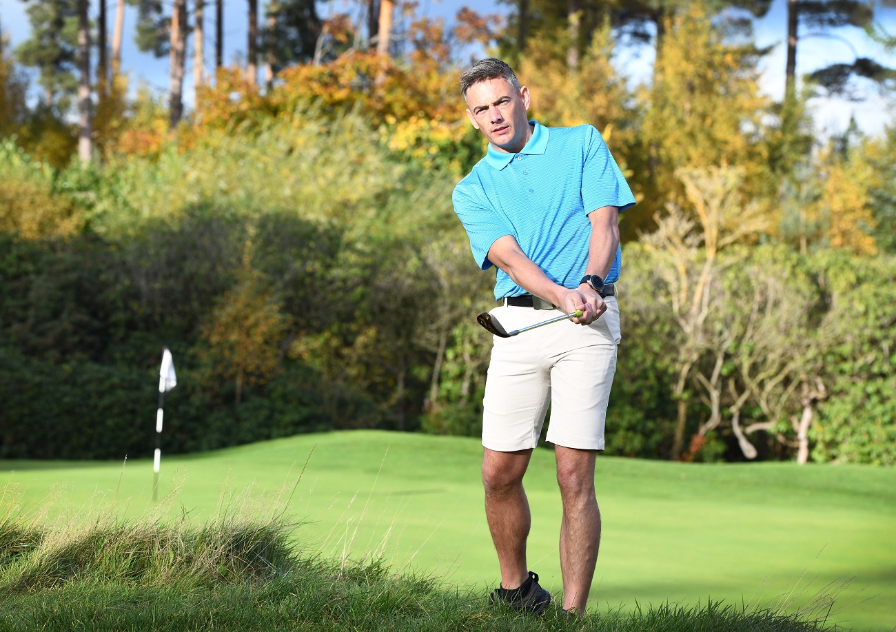 golfer wearing ProQuip shirt and shorts chips a ball